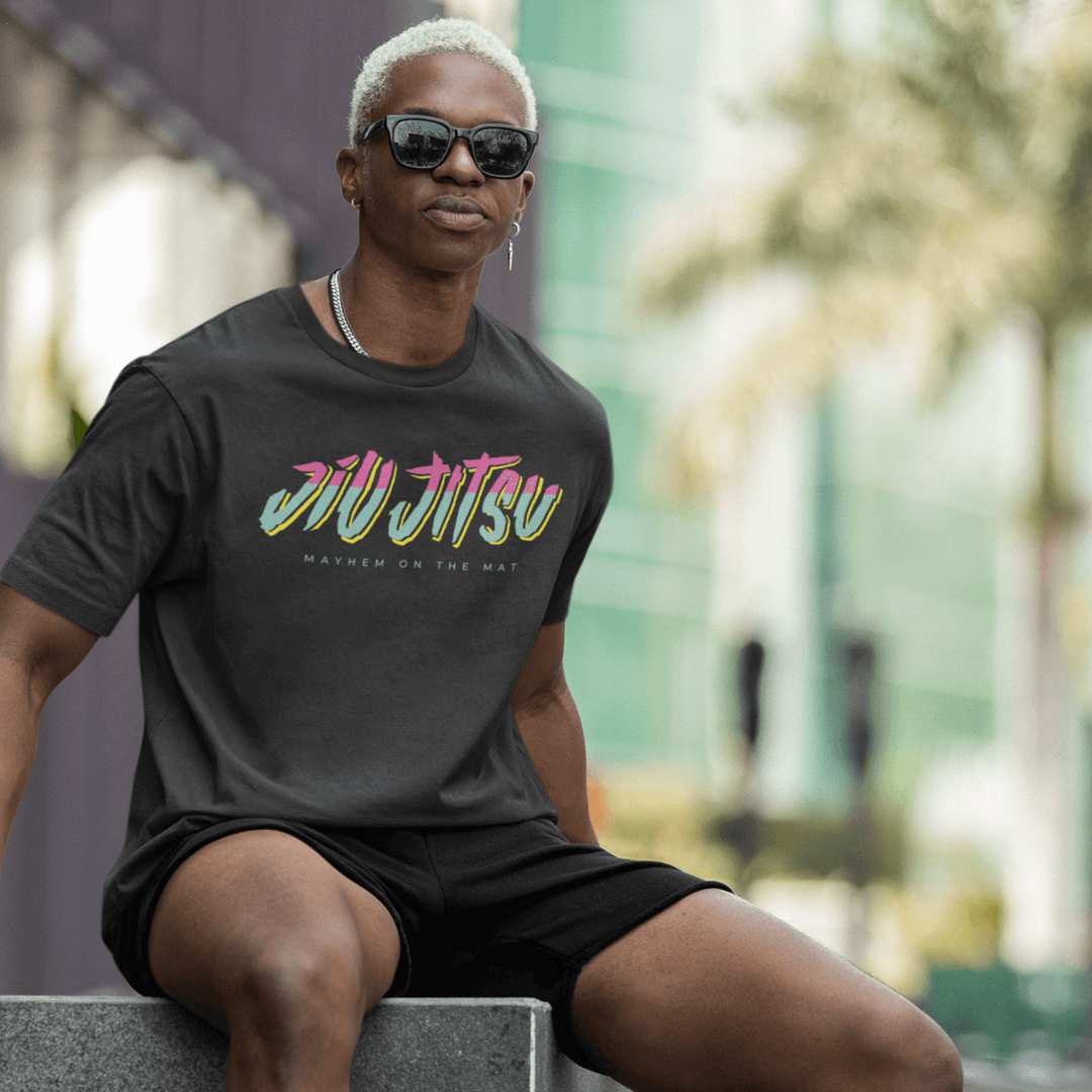 A person with short white hair wearing sunglasses and a "City Connect - Black" T-shirt sits outdoors on a ledge, embodying the spirit of community and camaraderie found in the martial arts world.