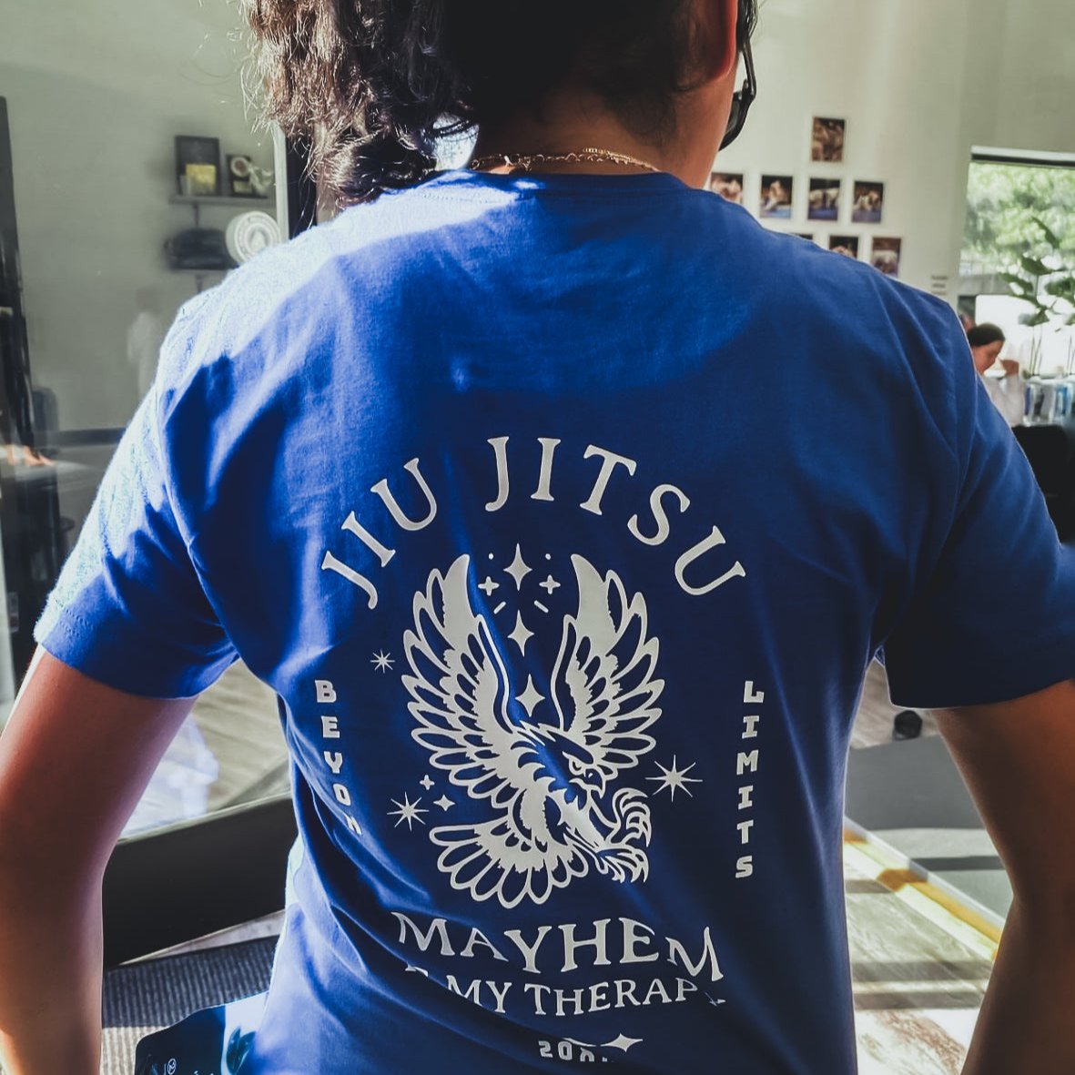 Wearing the Beyond Limits - Royal T-shirt, someone showcases a stylized eagle along with "Jiu Jitsu Mayhem," symbolizing their journey toward mental clarity through the art of Jiu Jitsu.