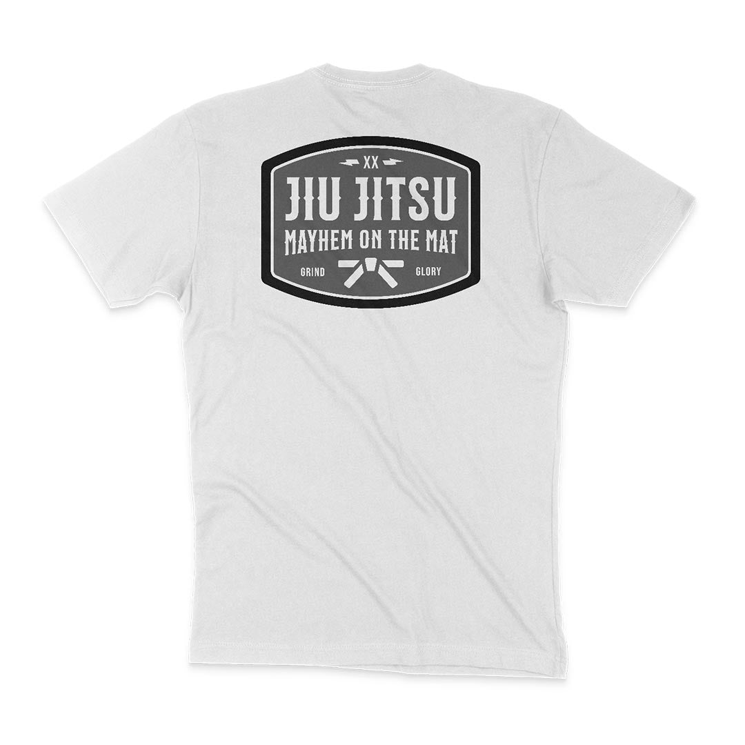 Back of a white T-shirt with a large black emblem containing the text "JIU JITSU MAYHEM ON THE MAT," and smaller text "GRIND" and "GLORY" at the bottom, exuding an old-school saloon vibe. Product Name: Mayhem Saloon - White