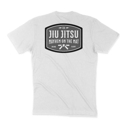 Back of a white T-shirt with a large black emblem containing the text "JIU JITSU MAYHEM ON THE MAT," and smaller text "GRIND" and "GLORY" at the bottom, exuding an old-school saloon vibe. Product Name: Mayhem Saloon - White