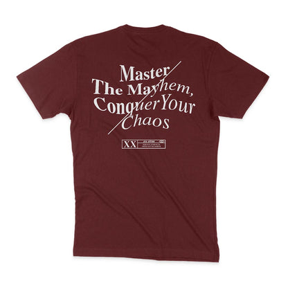 Back of a "Master The Mayhem / Conquer Your Chaos - Maroon" T-shirt with bold white text: "Conquer Your Chaos, Master the Mayhem," accompanied by smaller text near the bottom.