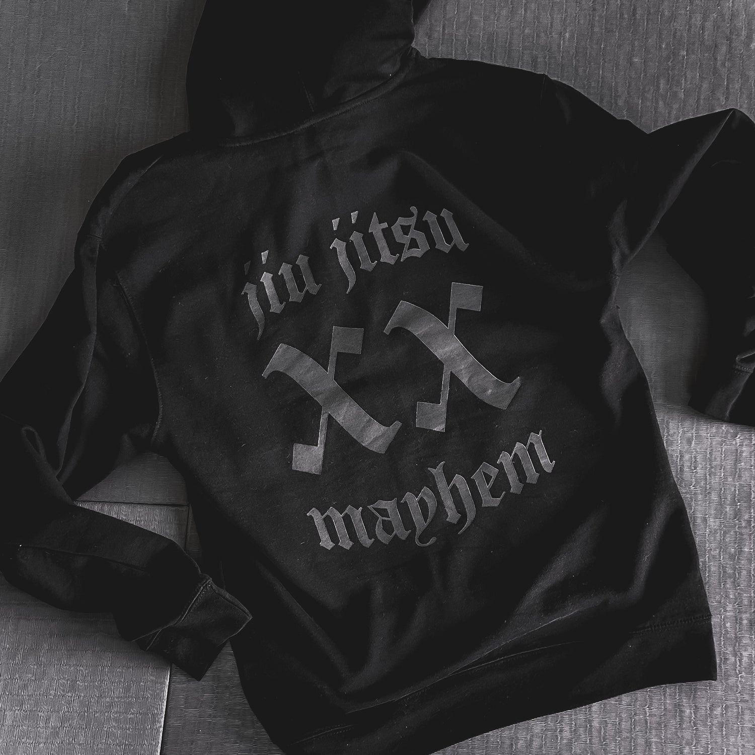 Smoke black hoodie on a gray surface featuring the bold, stylized "Team Mayhem" text on the back.